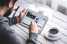 men looking at a tablet, with a cup of coffee on the table