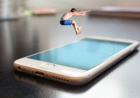 Miniature man jumping into a phone blue screen